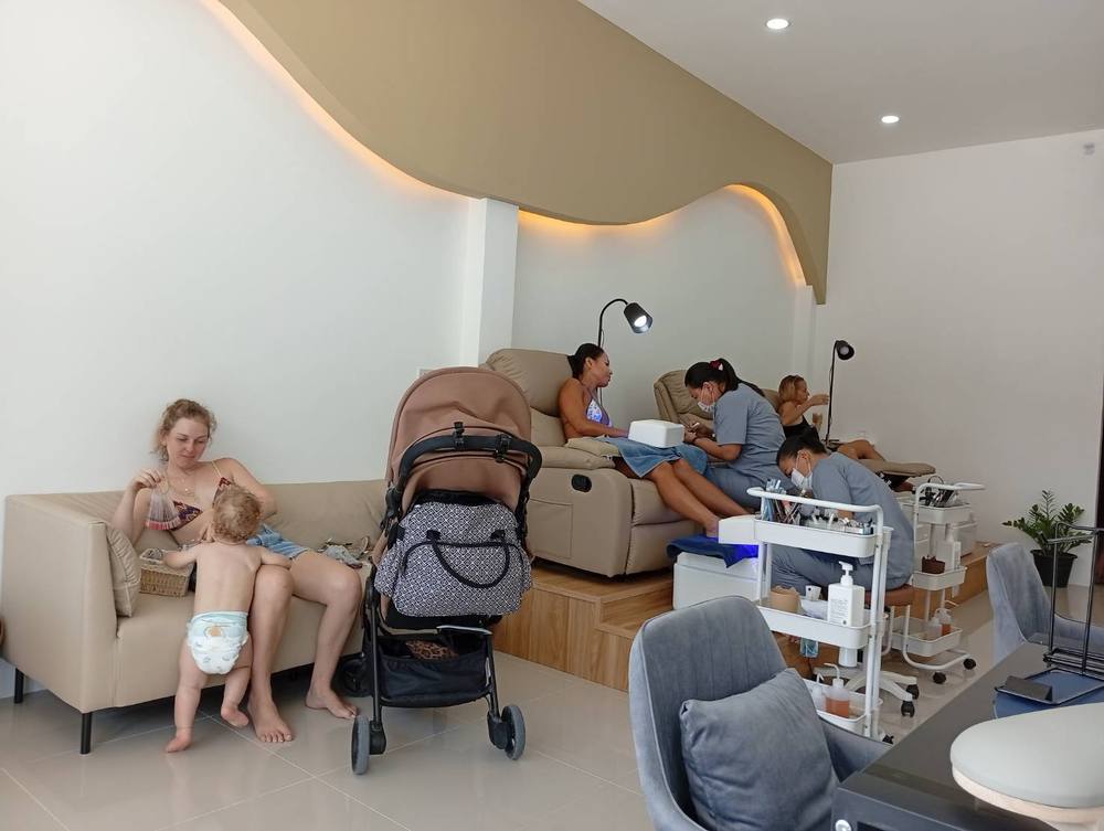 Guests relaxing in pedicure chairs while technicians work, natural daylight